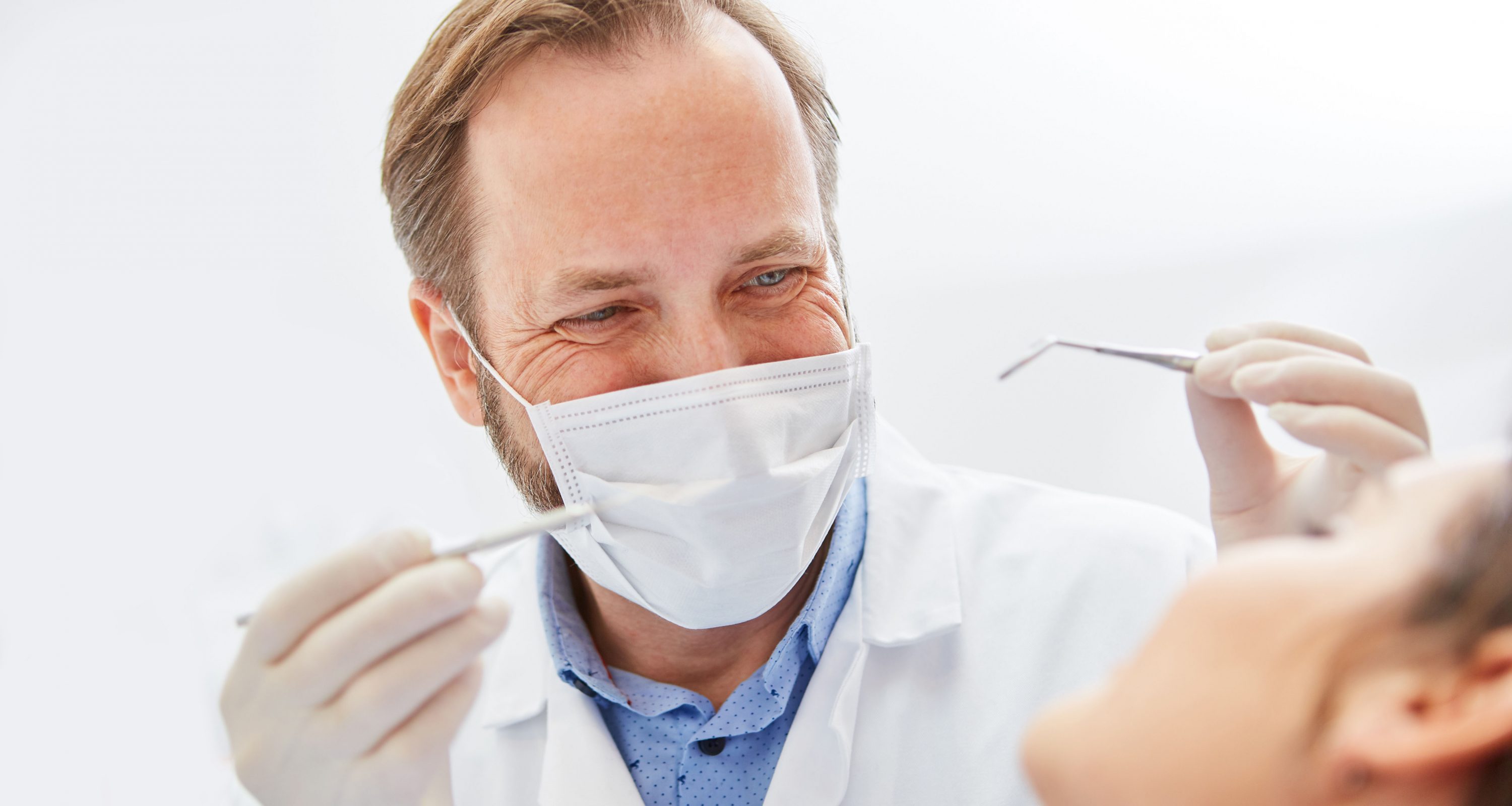 Zahnarzt mit chirurgischer Maske und Handinstrumenten